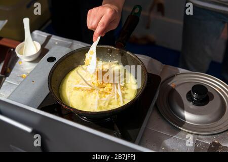 Homme inreconnaissable cuisine traditionnelle japonaise omelette avec des germes dans une rue de Fukuoka ville, japon Banque D'Images