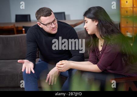 Jeune femme souriante en visite avec un thérapeute masculin pour la séance Banque D'Images