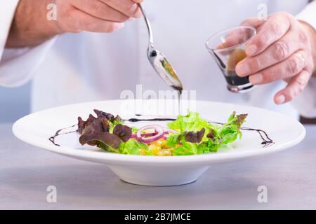 Chef mâle décorant un plat à salade avec du vinaigre Banque D'Images