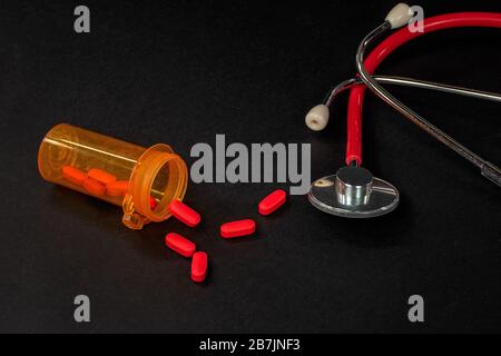 pilules rouges en bouteille d'ordonnance orange avec stéthoscope médical Banque D'Images
