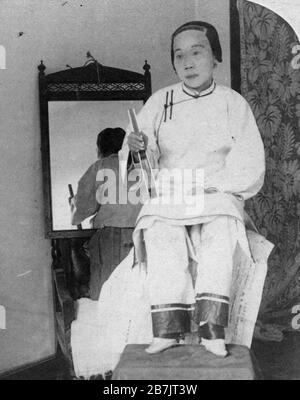 Cette dame chinoise de haute caste montre son lainty 'Lily feets' en 1899. Elle porte en fait de minuscules chaussons en soie sur ses très petits pieds. Pendant un millier d'années, les pieds des jeunes filles riches ont été cruellement cassés et les quatre plus petits orteils ont été enveloppés sous le gros orteil. Des yards de soie ont ensuite attaché le pied fermement. Tout cela pour créer ce qui était considéré comme la hauteur de la beauté pour les filles de caste supérieure afin qu'elles puissent attirer le meilleur mari possible plus tard. La liaison a été socialement encouragée alors qu'elle était également extrêmement douloureuse. Pour voir mes images vintage connexes, recherche: Prestor vintage China woman Banque D'Images