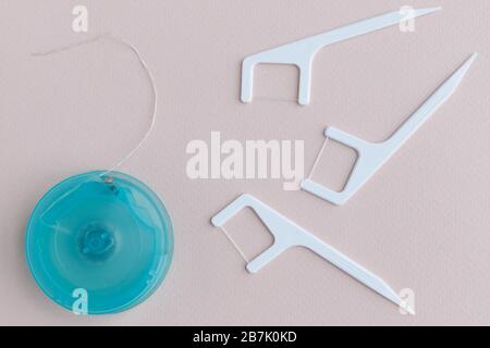 Vue de dessus du fil dentaire en boîte et du cure-dents en plastique jetable avec fil dentaire pour des soins interdentaires efficaces isolés sur fond rose clair. O Banque D'Images