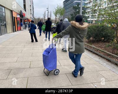 Corona virus, les gens qui attendent en ligne dans un supermarché à distance de reglementary Banque D'Images