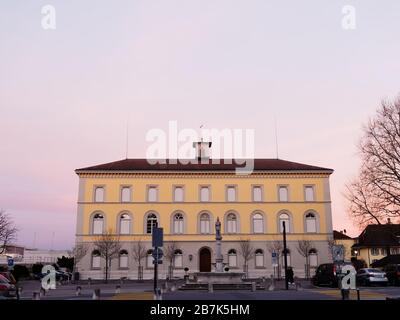 Façade de l'école primaire de Murten et fontaine avec statue devant Murten ou Morat en Suisse au crépuscule. Banque D'Images