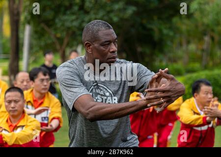 Dykembe Mutombo, avant, le joueur de basket-ball professionnel à la retraite congolais-américains joue du tai chi avec les gens à l'exercice du matin des 20 Banque D'Images