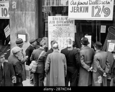 Un aviateur britannique fait partie d'un groupe de civils bondés autour de la fenêtre d'un magasin à Holborn, Londres, pour regarder une carte illustrant comment la RAF est en retour en Allemagne en 1940. Banque D'Images