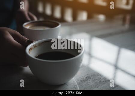 Gros plan image des mains tenant deux tasses blanches de café chaud sur la table dans le café Banque D'Images