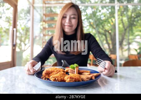 Gros plan d'une belle femme asiatique, dégustez du poulet frit et des frites au restaurant Banque D'Images
