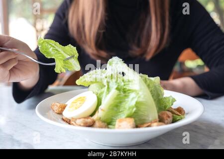 Gros plan image d'une femme mangeant une salade césar à la fourche sur la table dans le restaurant Banque D'Images