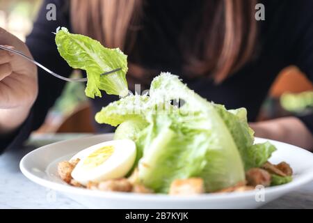 Gros plan image d'une femme mangeant une salade césar à la fourche sur la table dans le restaurant Banque D'Images