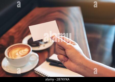 Une carte de visite vide blanche avec carnet et tasse à café sur table en bois Banque D'Images