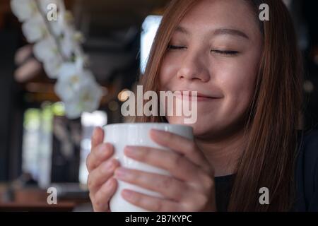 Gros plan image de la femme asiatique fermer les yeux pour sentir et boire du café chaud avec se sentir bon dans le café Banque D'Images