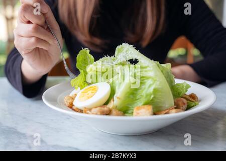 Gros plan image d'une femme mangeant une salade césar à la fourche sur la table dans le restaurant Banque D'Images