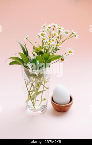 Oeuf bouilli dans une plaque en bois et un bouquet avec des daisies dans un verre transparent Banque D'Images