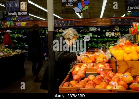 Bloomington, États-Unis. 16 mars 2020. Une femme âgée qui achète des oranges pendant la pandémie de Coronavirus, Shoppers remplit un magasin Kroger pour acheter des aliments chez les acheteurs de panique ont fait défricher les étagères quotidiennement en raison de la pandémie de Coronavirus à Bloomington. Crédit: SOPA Images Limited/Alay Live News Banque D'Images