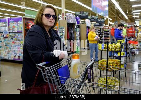 Bloomington, États-Unis. 16 mars 2020. Une femme attend dans une longue ligne de midi, Shoppers remplir un magasin Kroger pour acheter de la nourriture à des acheteurs de panique ont été défrichement sur une base quotidienne en raison de la pandémie de Coronavirus à Bloomington. Crédit: SOPA Images Limited/Alay Live News Banque D'Images