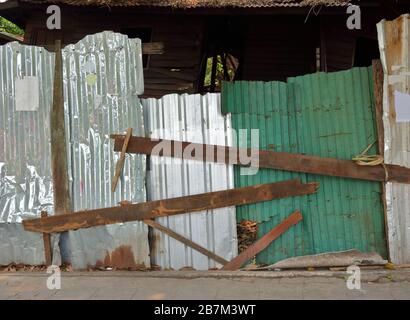 Tôle d'acier galvanisé ondulé en gros plan fixée par des barres de bois utilisées pour empêcher l'accès à la maison abandonnée Banque D'Images