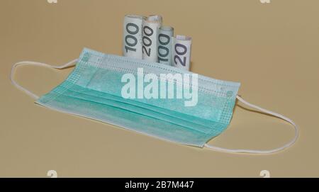 masque chirurgical uni et billets laminés dans les rolles près de l'isolé sur fond pastel concept de prix élevé des produits médicaux. Banque D'Images