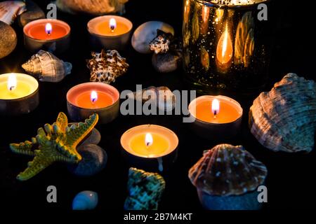 Bougies, pierres et coquillages au spa, lumière la nuit Banque D'Images