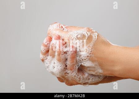 Laver les mains avec du savon sur fond gris. Prévention de l'hygiène désinfection du virus du coronavirus. Gros plan. Banque D'Images