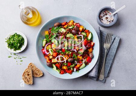 Salade de lentilles avec mélange de légumes dans un bol. Arrière-plan gris. Vue de dessus. Banque D'Images