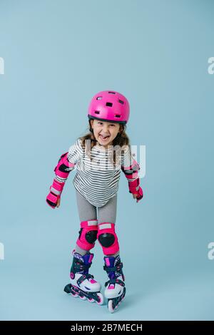 Plein de bonheur fille rollerblading à l'intérieur sur fond bleu Banque D'Images