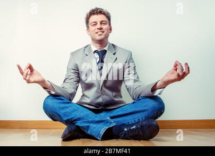 Portrait d'un travailleur indépendant faisant des exercices de relaxation à la maison assis à plusieurs pattes et les bras débordés Banque D'Images