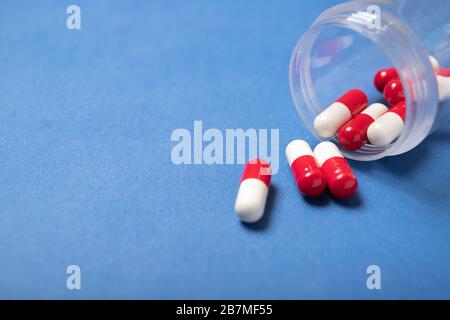 Bol avec capsules sur fond bleu. Rhumes, toux. Coronavirus. Médecine et santé Banque D'Images