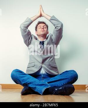 Portrait d'un travailleur indépendant faisant des exercices de relaxation à la maison assis à plusieurs pattes et les bras débordés Banque D'Images