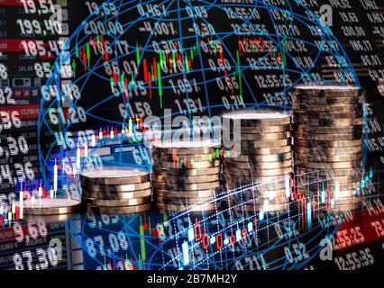 Pile de pièces devant un tableau et graphiques avec taux de change Banque D'Images