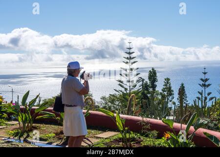 Femmes matures regardant la vue sur Funchal Madeira, Portugal debout sur une levada et avec la montagne et un ciel nuageux en arrière-plan. Banque D'Images