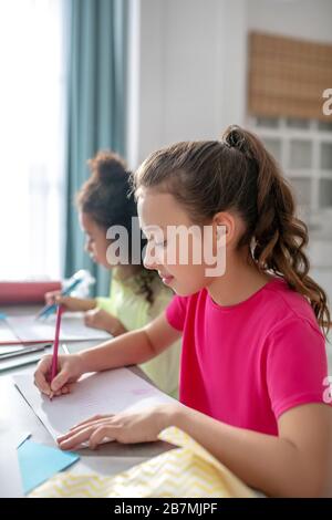 Deux filles du même âge dessinant à la table. Banque D'Images