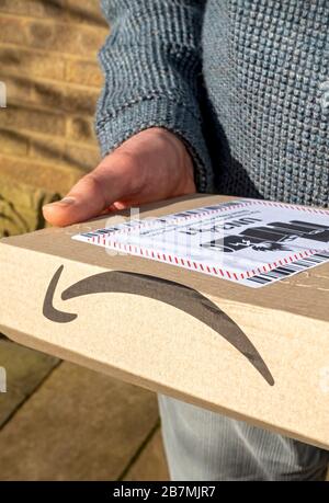 Gros plan de la personne homme livrant en ligne Amazon emballage livraison avec batterie lithium-ion étiquette d'avertissement Angleterre Royaume-Uni Royaume-Uni Grande-Bretagne Banque D'Images