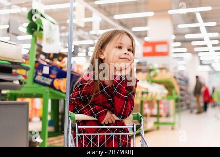 Une jeune fille gaie tient un panier et sélectionne les produits à la maison. Le concept de shopping au supermarché, sélection de produits, ventes. Banque D'Images