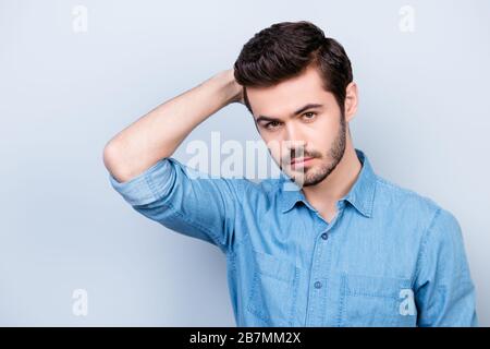 Gros plan photo portrait d'un homme sérieux dans un Jean bleu chemise, touchant ses cheveux parfaits. Derrière lui se trouve un espace de copie Banque D'Images