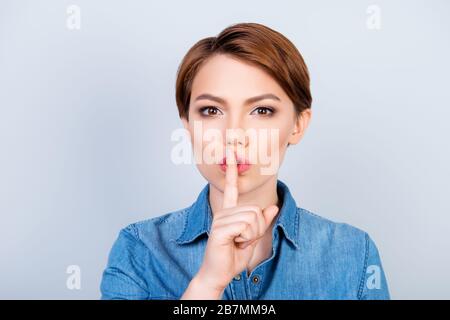 SHH ! Fille montre à quelqu'un de rester calme et de dire son secret sur fond bleu clair