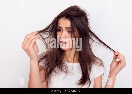 Gros plan portrait d'une jeune femme frustrée de brunette avec des cheveux bousillé sur fond blanc Banque D'Images