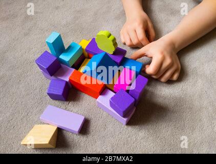 Un enfant joue avec un coeur coloré avec des blocs de construction en bois colorés. Concept de journée mondiale de sensibilisation à l'autisme. Banque D'Images