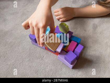 Un enfant joue avec un coeur coloré avec des blocs de construction en bois colorés. Concept de journée mondiale de sensibilisation à l'autisme. Banque D'Images