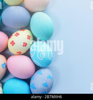 Oeufs de chasse de Pâques colorés teints par l'eau de couleur avec beau motif sur fond bleu pastel, design concept de vacances, vue de dessus, espace de copie. Banque D'Images