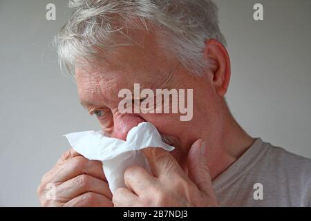 L'homme malade utilise un tissu pour souffler son nez Banque D'Images