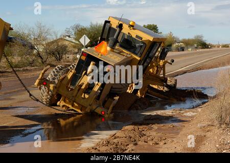 Un niveleur qui s'est coincé dans la boue le long d'une route d'Arizona après les pluies de mousson. Banque D'Images