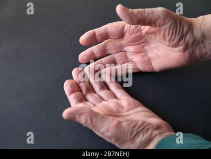 Les mains de l’homme plus âgé sur une surface sombre avec un espace de copie Banque D'Images