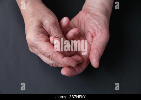 Un homme plus âgé tient ses doigts douloureux sur un fond sombre avec de la place pour le texte Banque D'Images