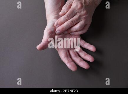 Un homme plus âgé indique une zone de douleur sur son pouce Banque D'Images