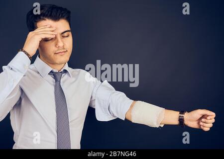 Jeune homme avec maux de tête et bandage sur la main Banque D'Images