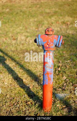Gros plan vertical d'une vieille arroseur d'eau rouillée une zone herbeuse Banque D'Images