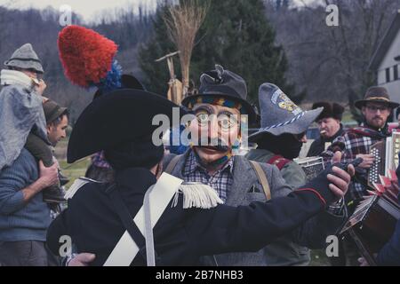 Deux hommes masqués dansant avec un groupe traditionnel en arrière-plan. Concept de musique folk. Défilé de carnaval de Pust. Banque D'Images