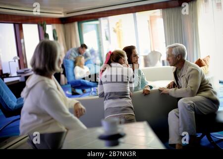 Homme adulte moyen parlant à ses deux filles adolescentes avec sa femme dans un salon. Banque D'Images