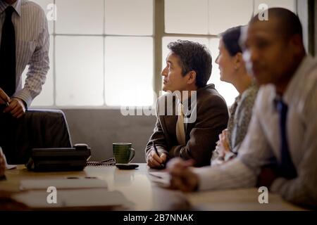 Homme d'affaires adulte mûr assis avec des collègues dans une salle de conférence. Banque D'Images